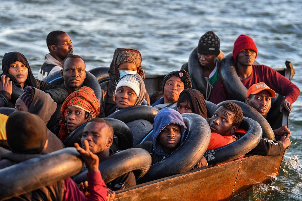 Migrants from sub-Saharan Africa sit in a makeshift boat as they are found by Tunisian authorities off the coast of Tunisia's Sfax on 4 October 2022 (AFP)