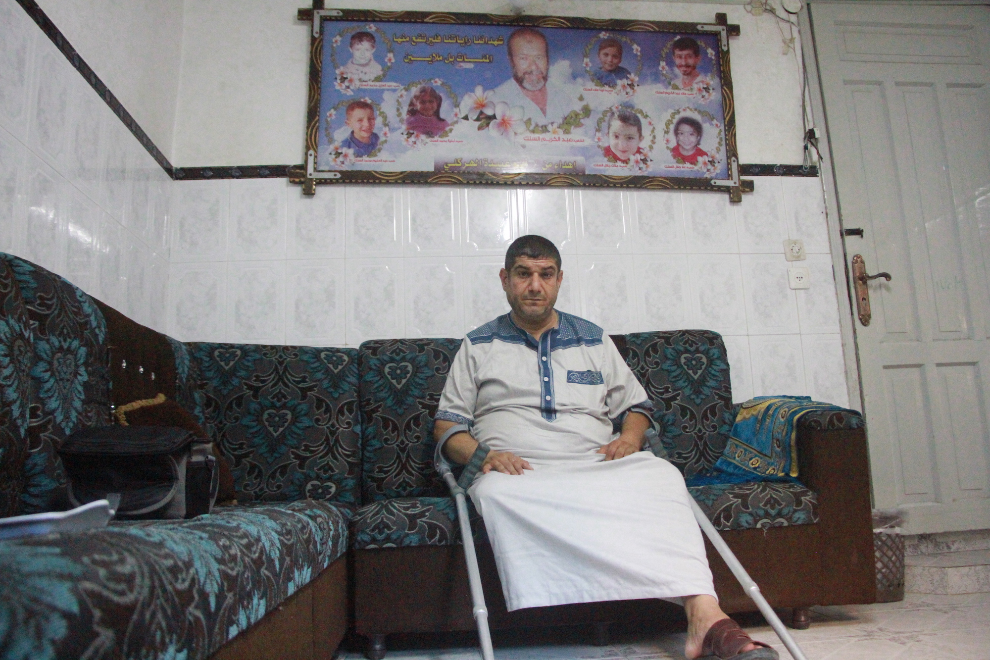 Mohammed Al-Silk poses in front of photos of his children, father and nephews who were killed on the rooftop of his house during Israel's 2014 air strikes on Gaza (MEE/Ahmed Al-Sammak)