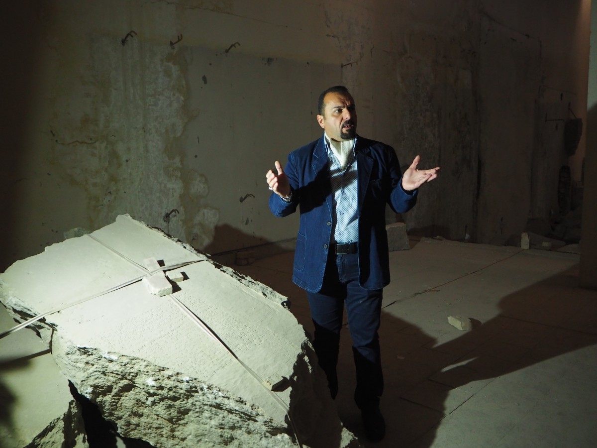 Mosul Museum Director Zeid al-Obeidi stands beside a large piece of the Ishtar Lion statue destroyed by IS (MEE/Tom Westcott)