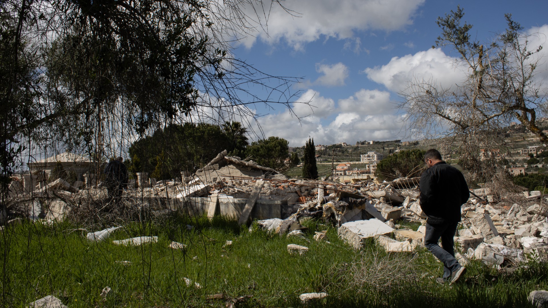 Nour Ghacham walks among Najwa's olive trees. Much of Yaroun has been razed to the ground by Israel (MEE/Hanna Davis)