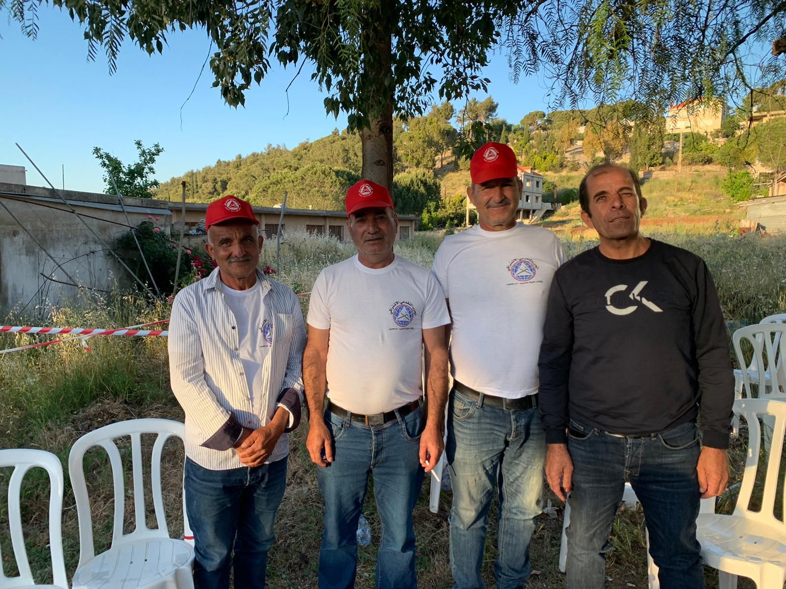 Four men wearing PSP apparel stand outside a voting poll in Lebanon in the town of Ibl al-Saqi in the Marjayoun district in southern Lebanon (MEE/AJ Naddaff)