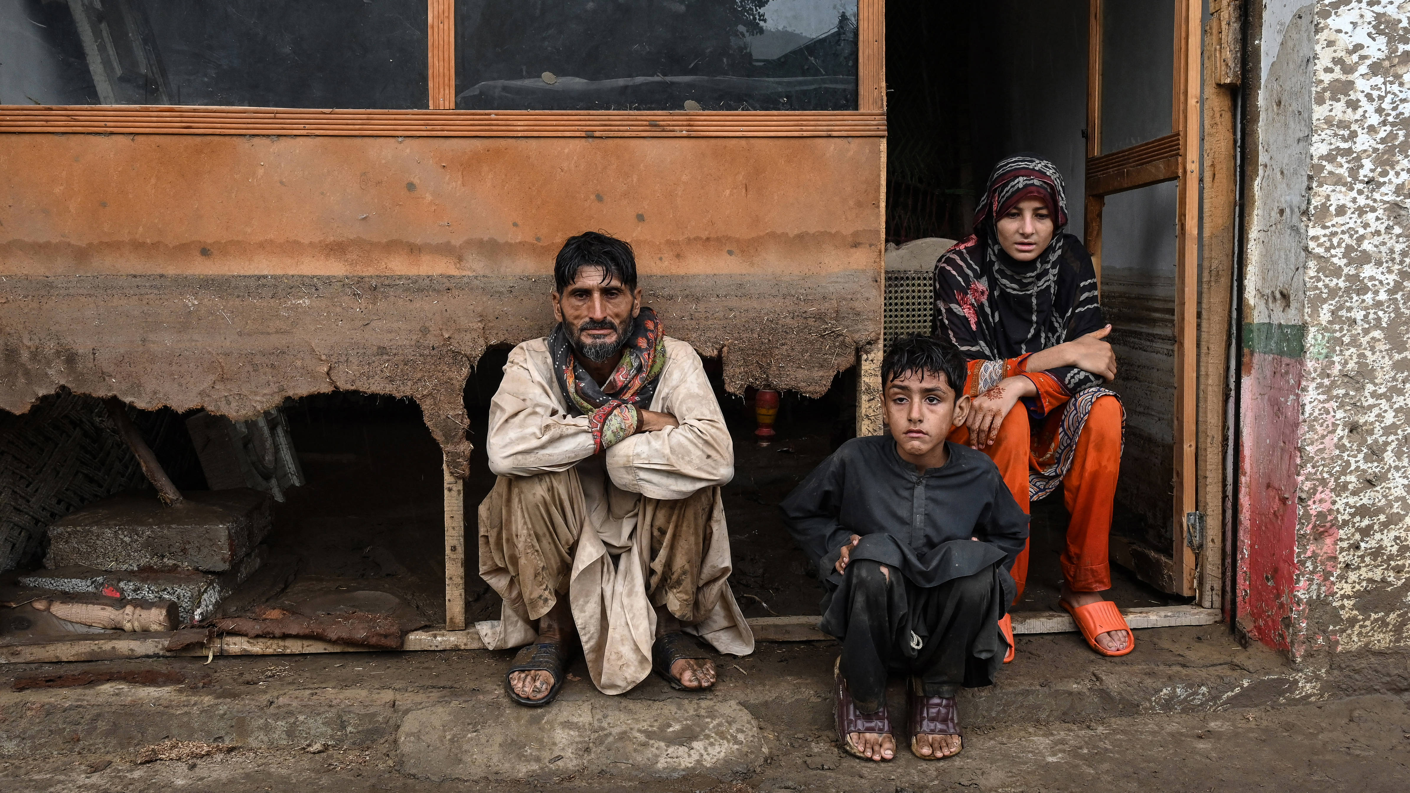 Members of a family sit outside their damaged shop after the Buner district of Pakistan's Khyber Pakhtunkhwa province was hit by a flash flood on 18 August (Abdul Majeed/ AFP)