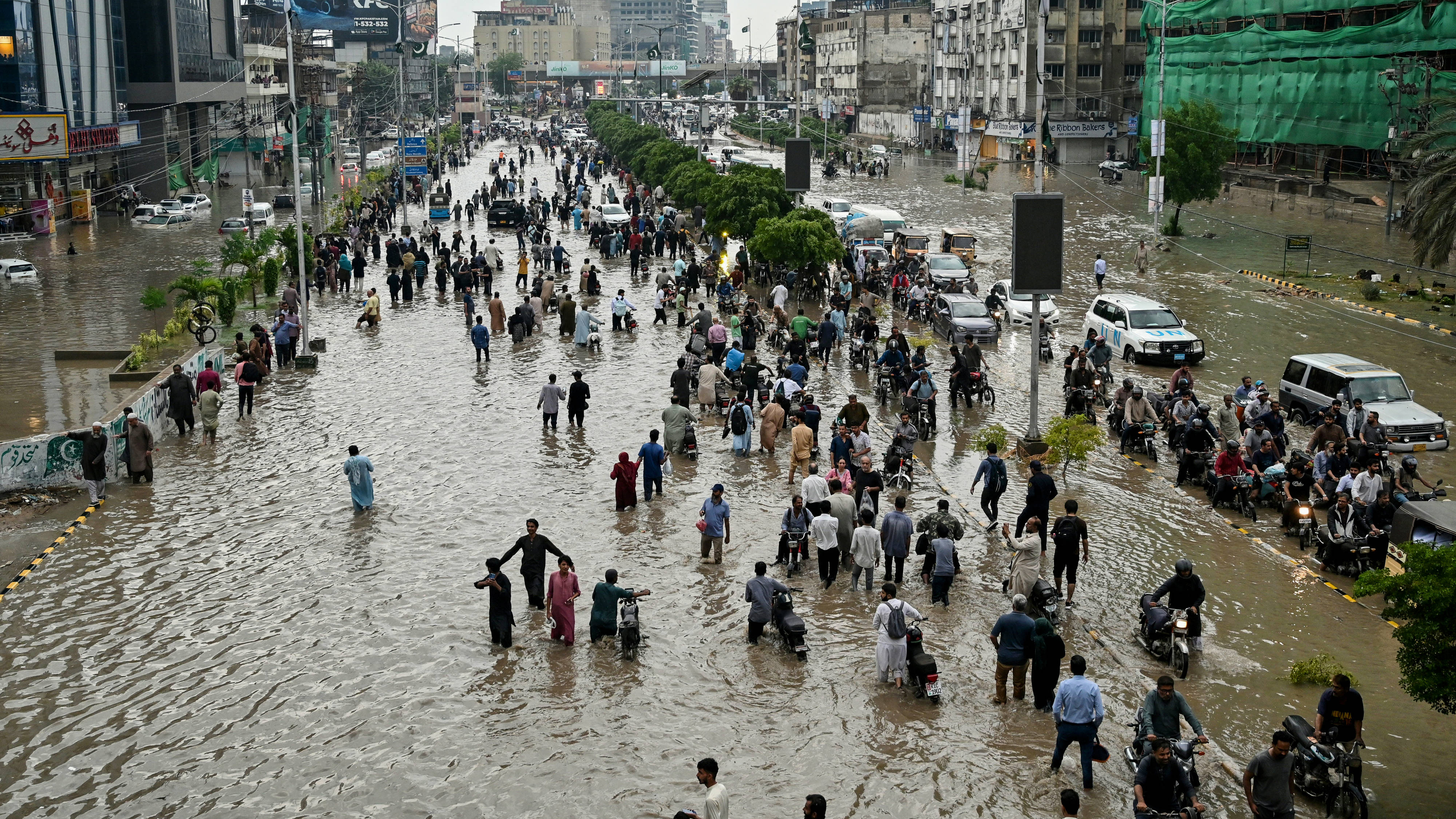 People wade through a flooded street after heavy rainfall in Karachi on 19 August (Asif HASSAN / AFP)