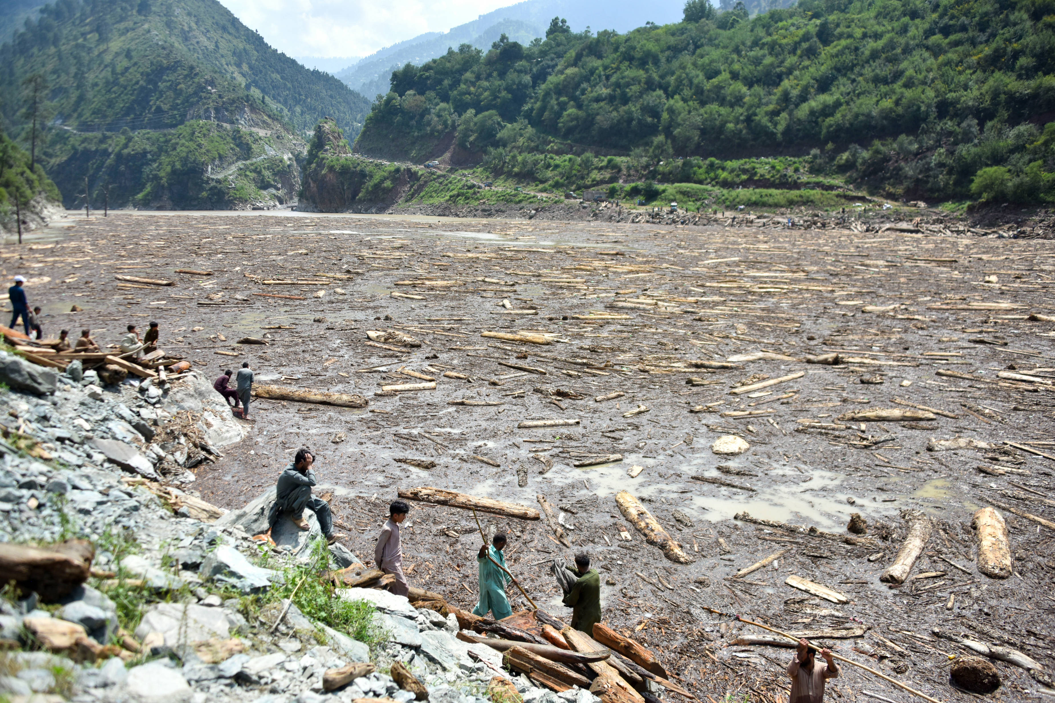 Locals collect wood in aftermath of flash flood from Noseri Dam near Muzaffarabad, the capital of Pakistan-administered Kashmir, on 16 August (Sajjad Qayyum/ AFP)