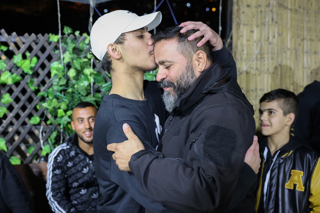 Palestinian Mohammed al-Awar (L), released from an Israeli jail in exchange for hostages freed by Hamas in Gaza, kisses his father upon return to his home in east Jerusalem, 26 November 2023 (AFP)
