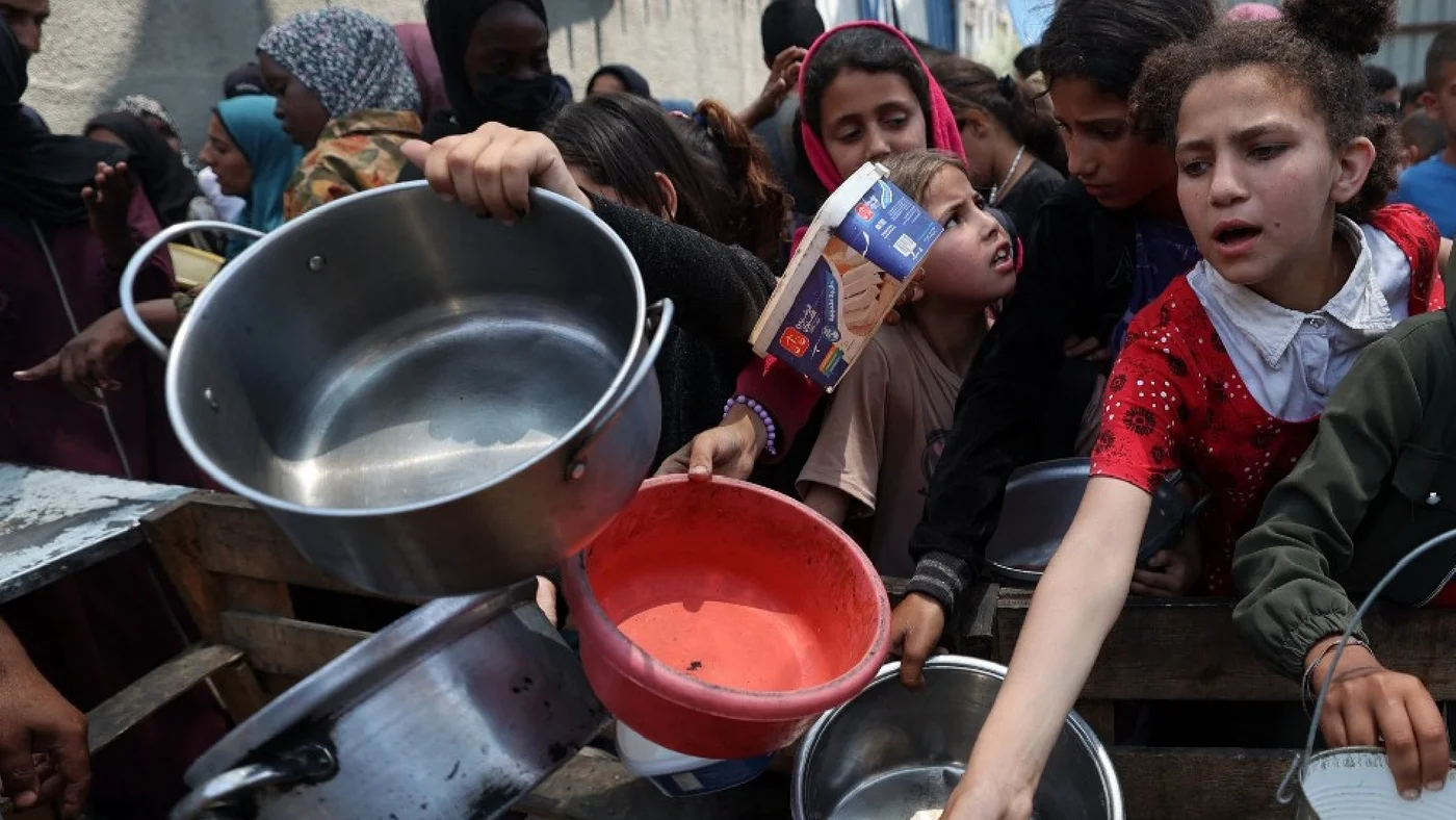 Palestinian children gather at a hot meal distribution point in Nuseirat in the central Gaza Strip, 4 June 2025 (AFP)