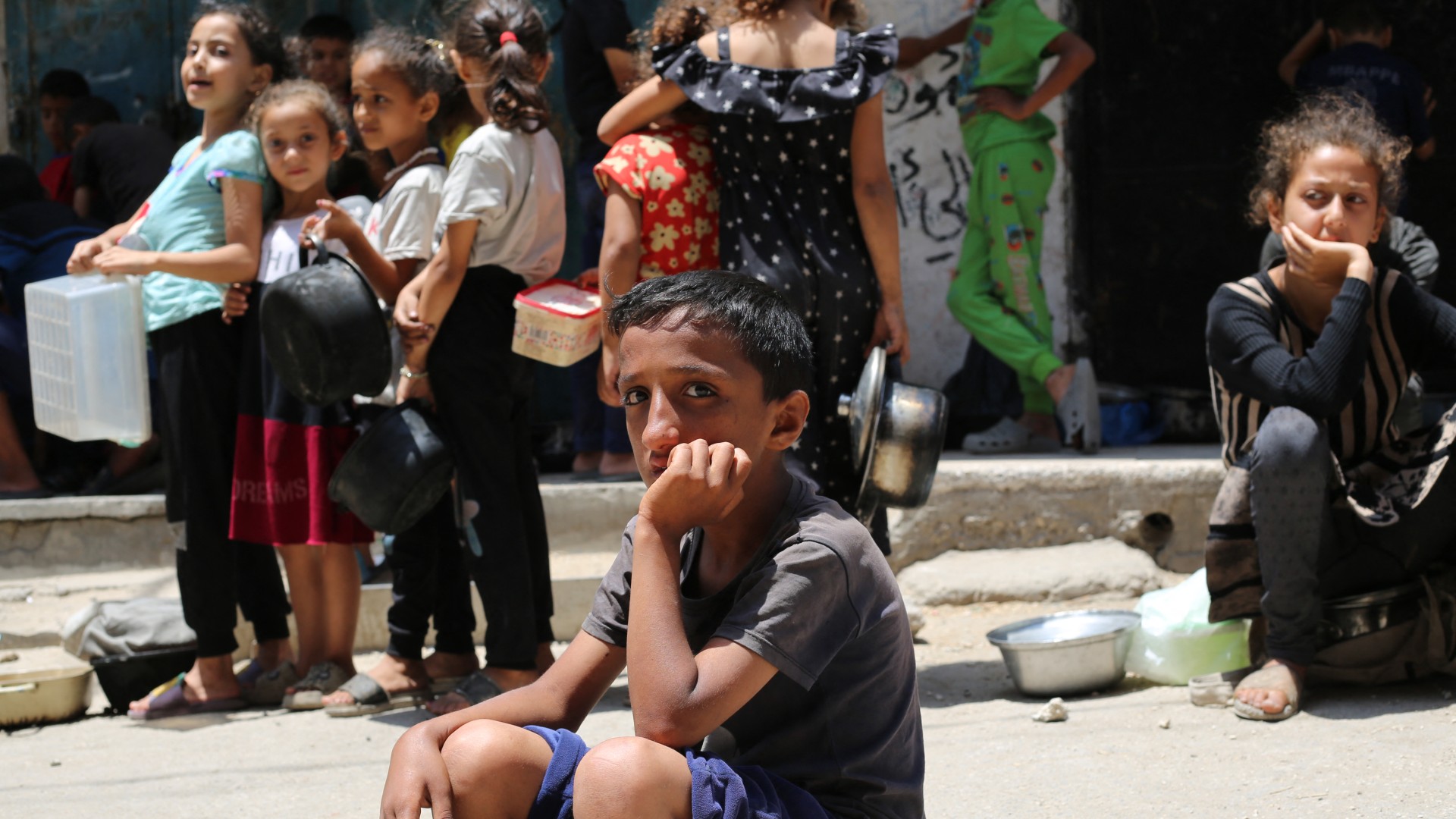 Palestinian children wait at a food distribution point in Nuseirat, in the central Gaza Strip, on June 23, 2025.