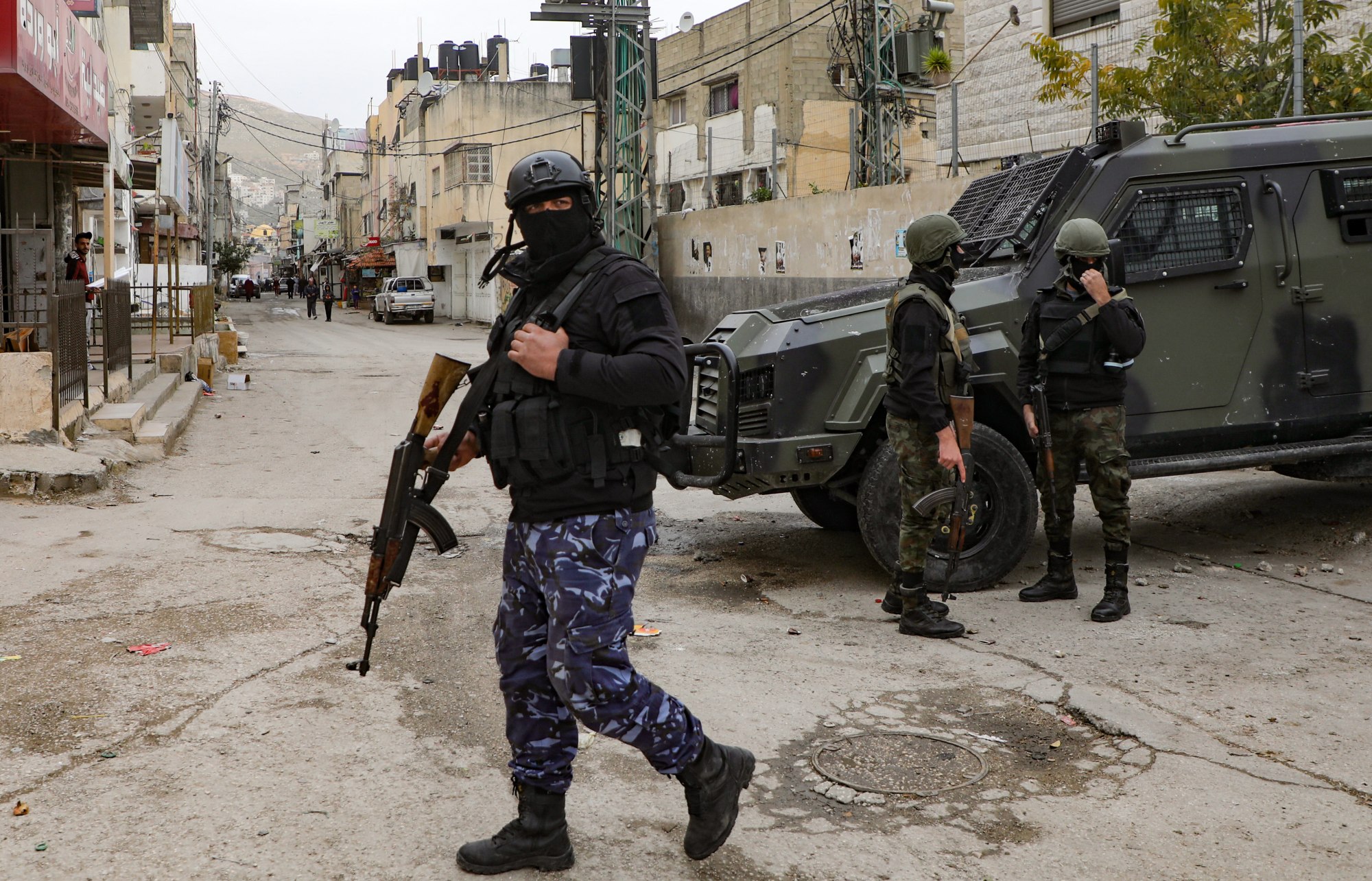 Palestinian Authority security forces in balaclavas stand by an armoured vehicle at the entrance to Balata camp, near the occupied West Bank city of Nablus, on 15 December 2020 (AFP)