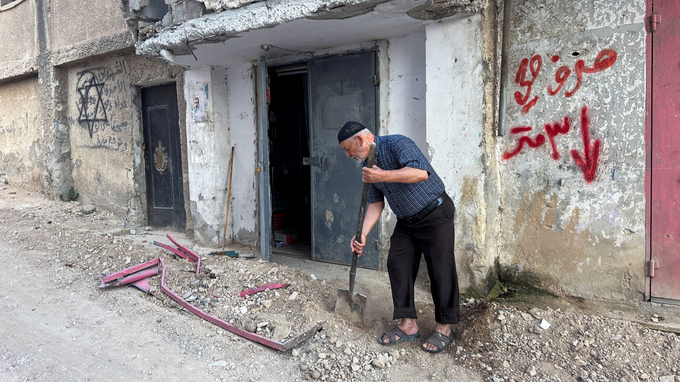 A Palestinian man removes rubble in front of his house in Jenin, 6 September 2024 (Reuters)