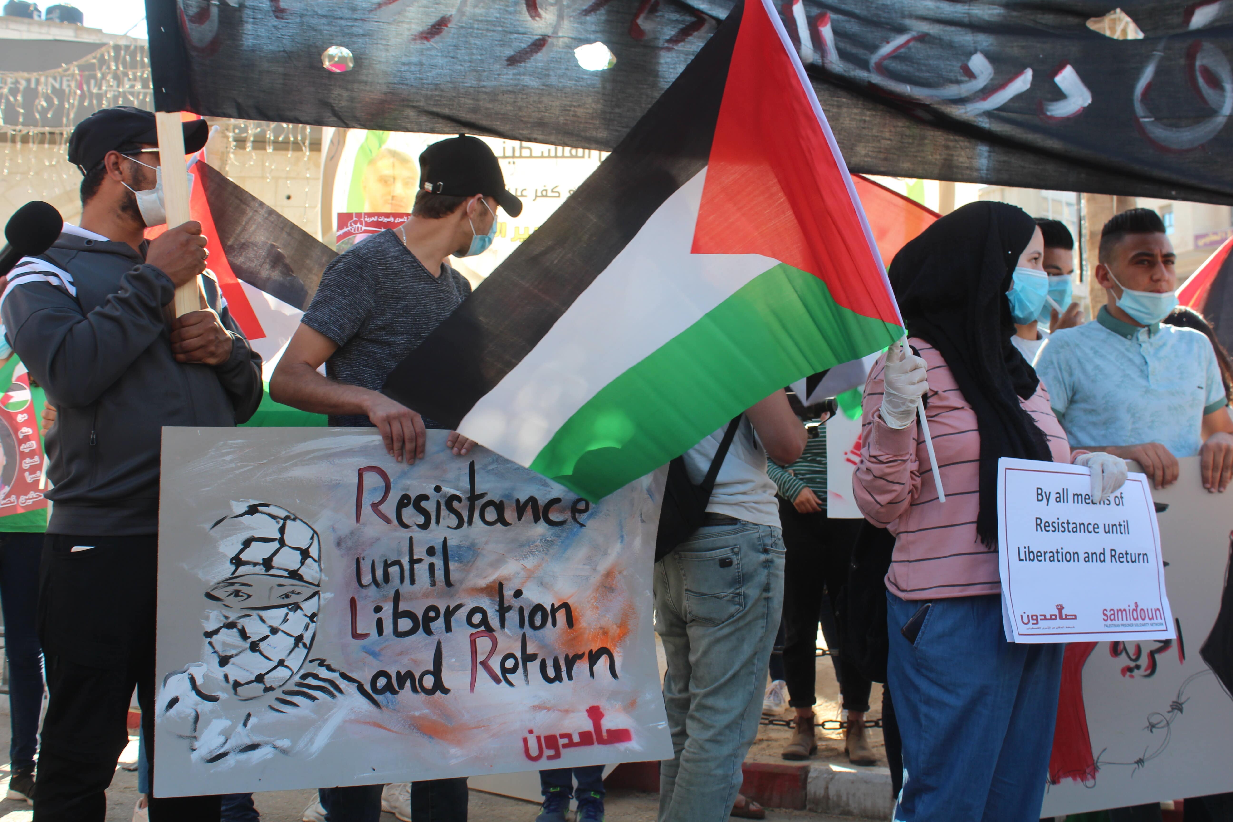 A group of young Palestinians wearing protective masks and gloves protest in the West Bank city of Ramallah (MEE)