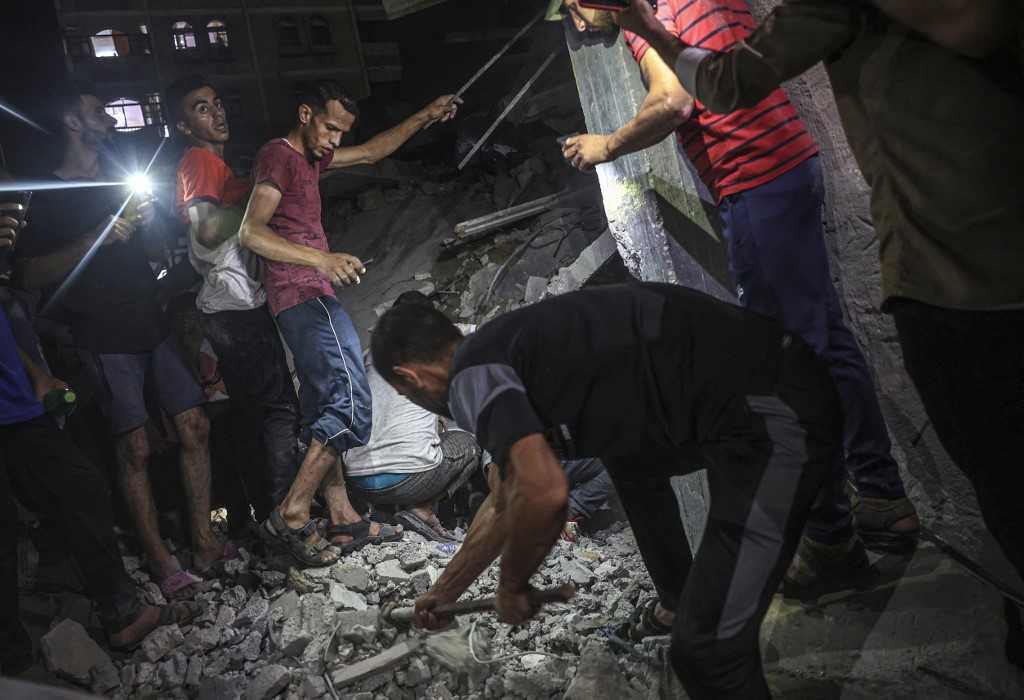 Palestinians search for casualties in the rubble of a residential building following a reported Israeli strike in Rafah in the southern Gaza Strip, 6 August 2022 (AFP)
