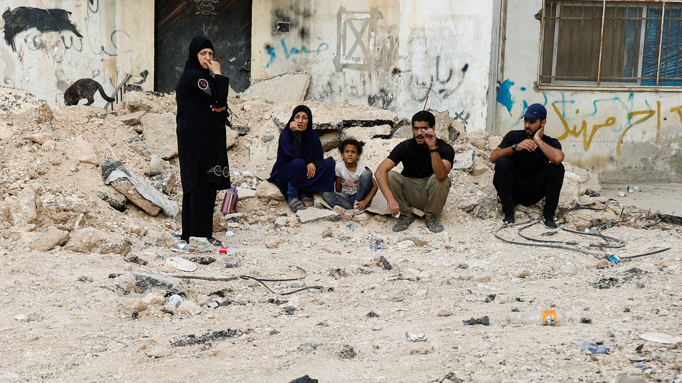 Palestinians sit by a damaged road in Jenin camp, 6 September 2024 (Reuters)