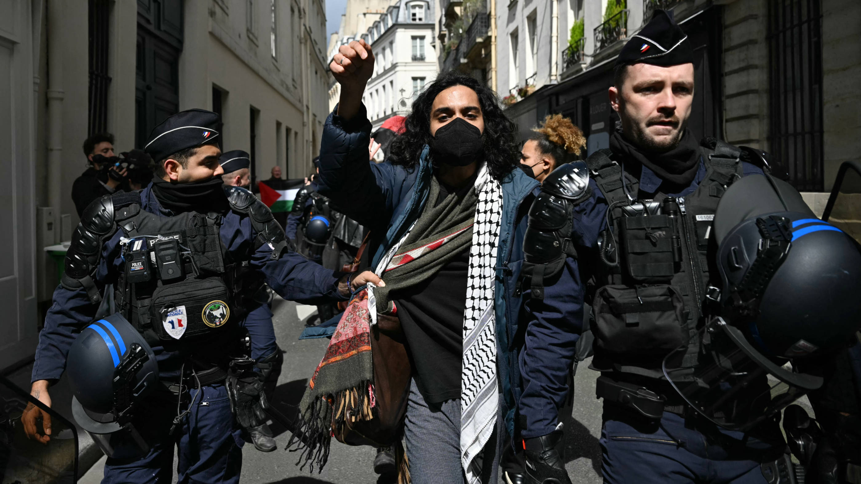 A protester is escorted away by French gendarmes during the evacuation of a pro-Gaza sit-in in the entrance hall of Sciences Po university on 3 May 2024 (AFP)