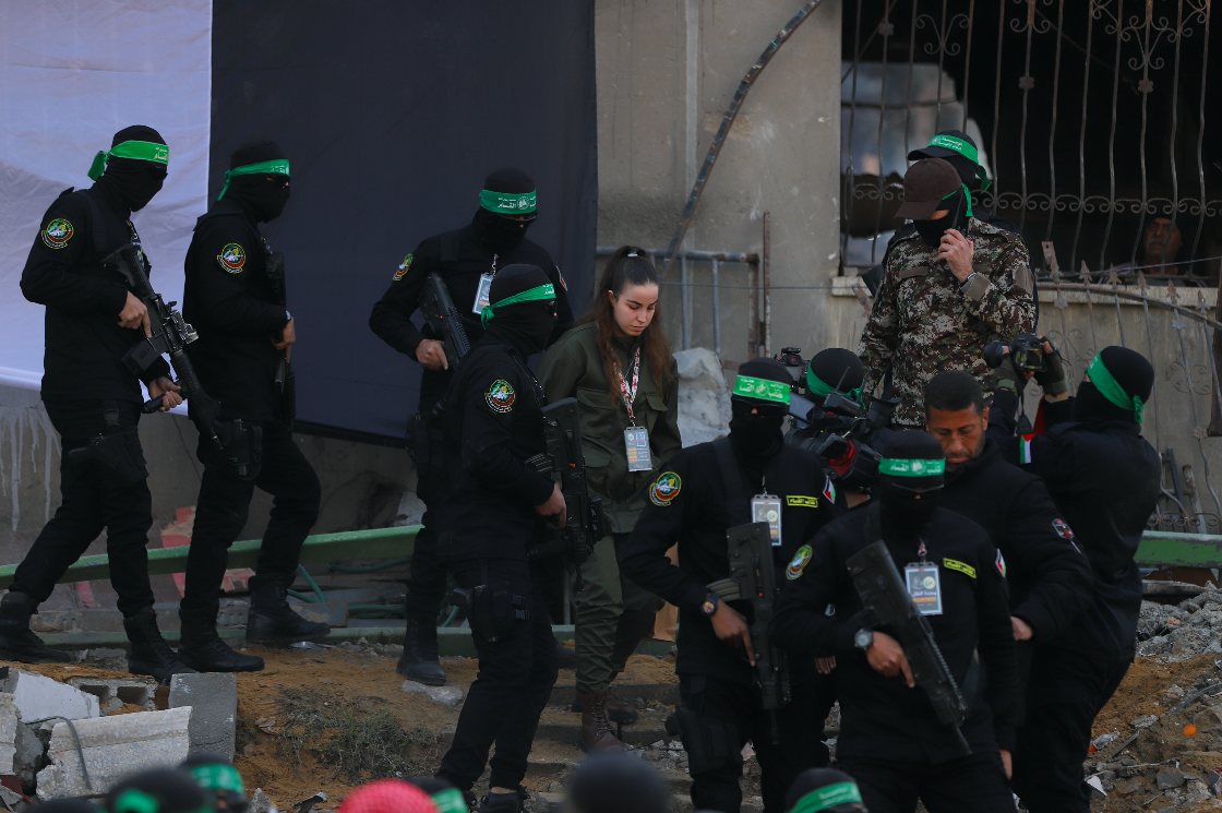 Hamas fighters escort Israeli captive Agam Berger on a stage before handing her over to a Red Cross team in Jabalia on January 30, 2025. (Mohamed al-Hajjar)