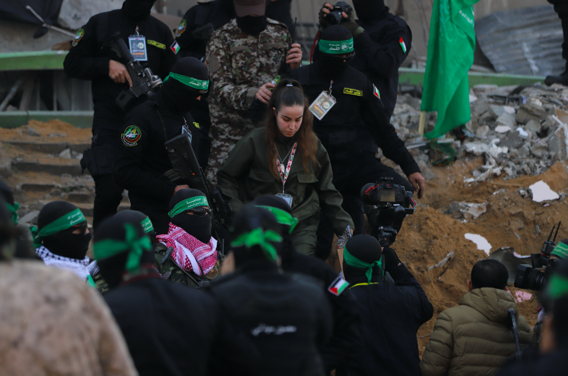Hamas fighters escort Israeli captive Agam Berger on a stage before handing her over to a Red Cross team in Jabalia on January 30, 2025. (Mohamed al-Hajjar)