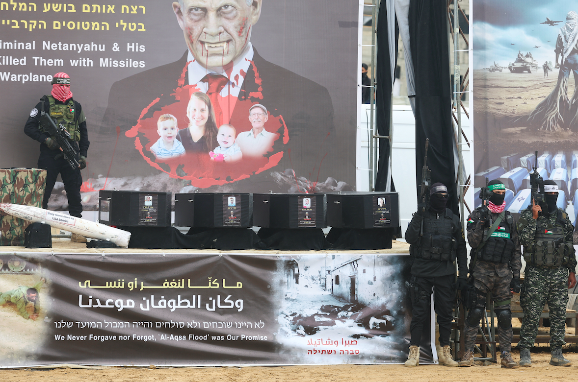 Hamas fighters stands on stage near coffins during the handover of four Israeli captives' bodies in Khan Younis in the southern&nbsp;Gaza&nbsp;Strip, February 20, 2025. (REUTERS/Ramadan Abed)