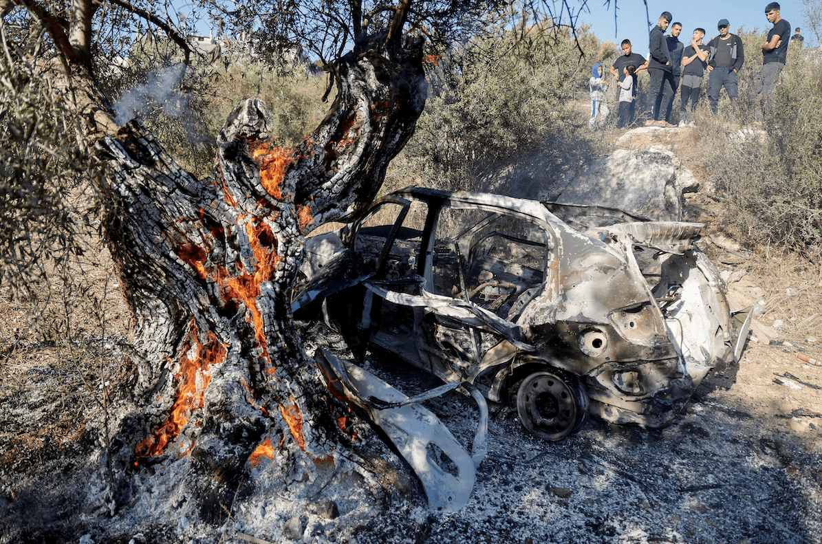 People look at a burnt vehicle at the site where Israeli forces killed three Palestinians, near Jenin, in the Israeli occupied West Bank October 28, 2025. REUTERS