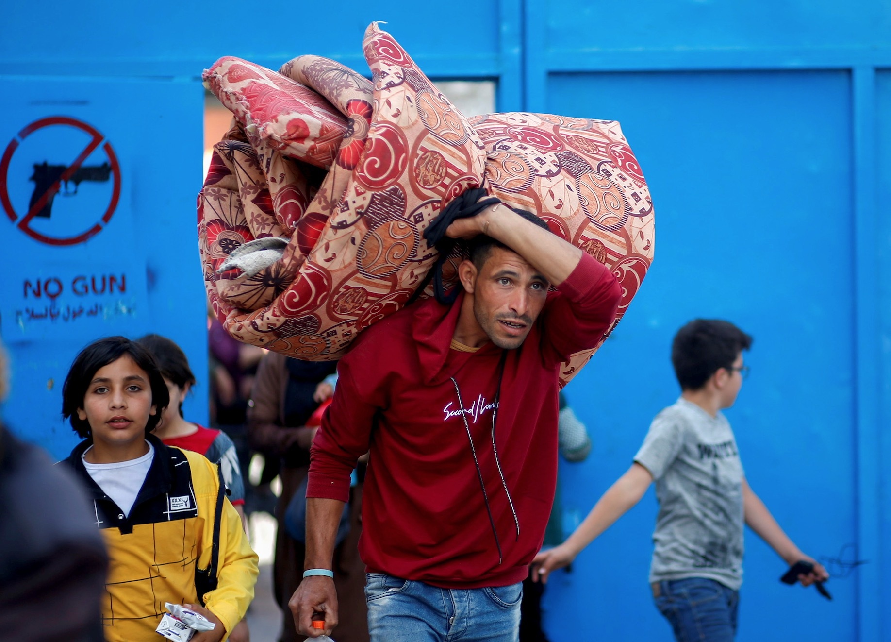 A Palestinian man carries his belongings after being forced to flee home (Reuters)