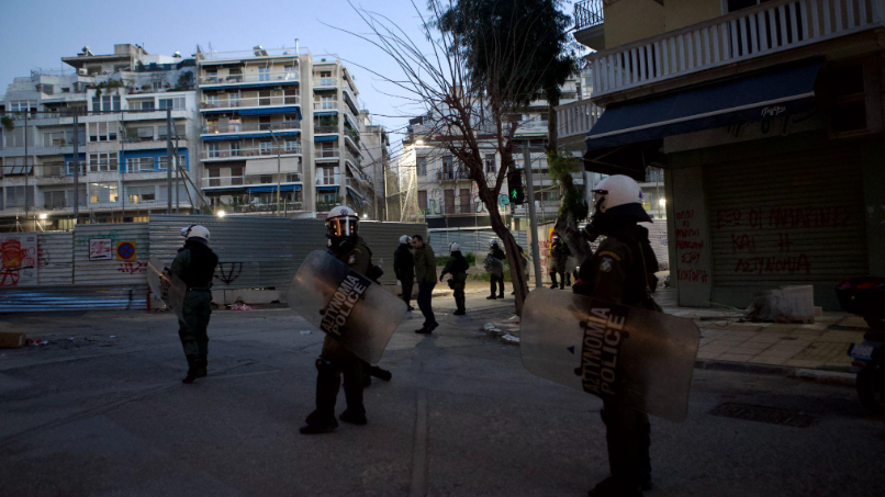 Riot police patrol the area after a protest in front of the Metro construction site in Exarcheia, Athens