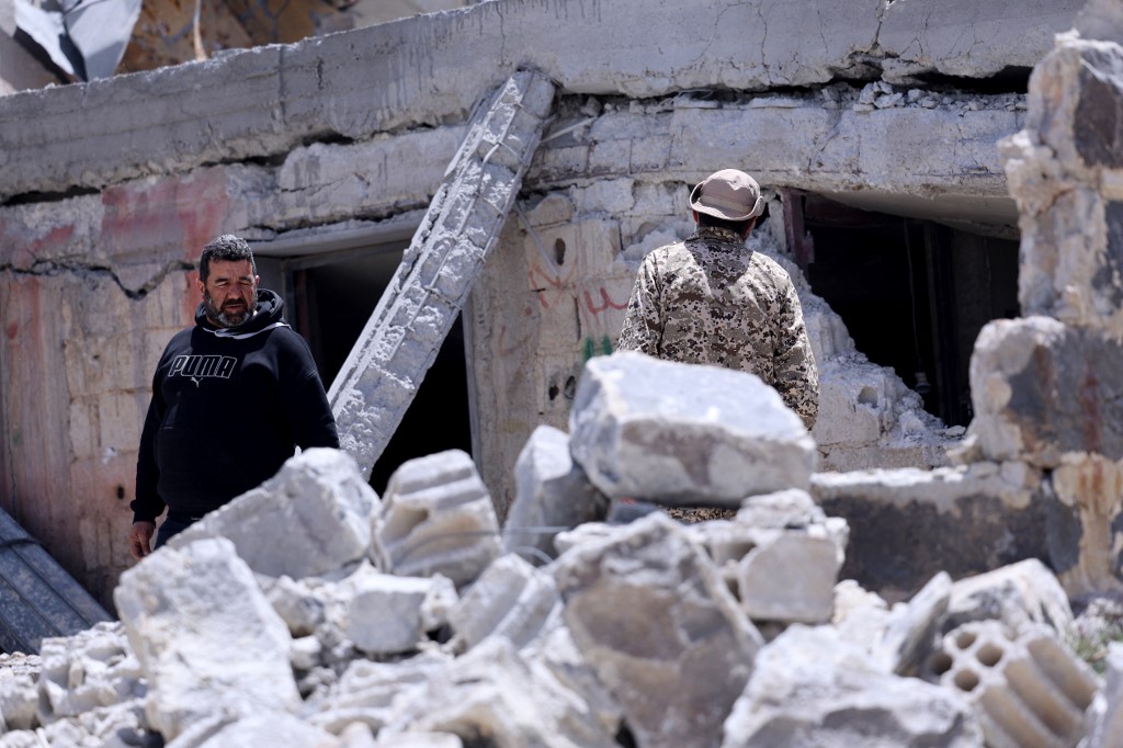 Men look at the debris following a Jordanian strike on reported drugs and weapons storage facilities in the village of Arman, in the southern Druze-majority province of Sweida, of which many parts are outside the control of Damascus, on 3 May 2026 (Shadi al-Dubaisi/AFP)