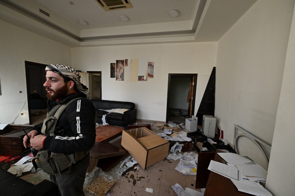 A Syrian rebel stands inside a ransacked office at the Defence Ministry's military security headquarters in the Damascus district of Kafr Sousa on December 9, 2024.