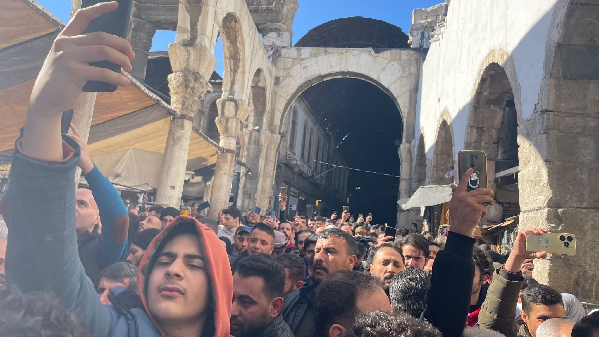 Crowds pass by Roman Ruins in Old City 