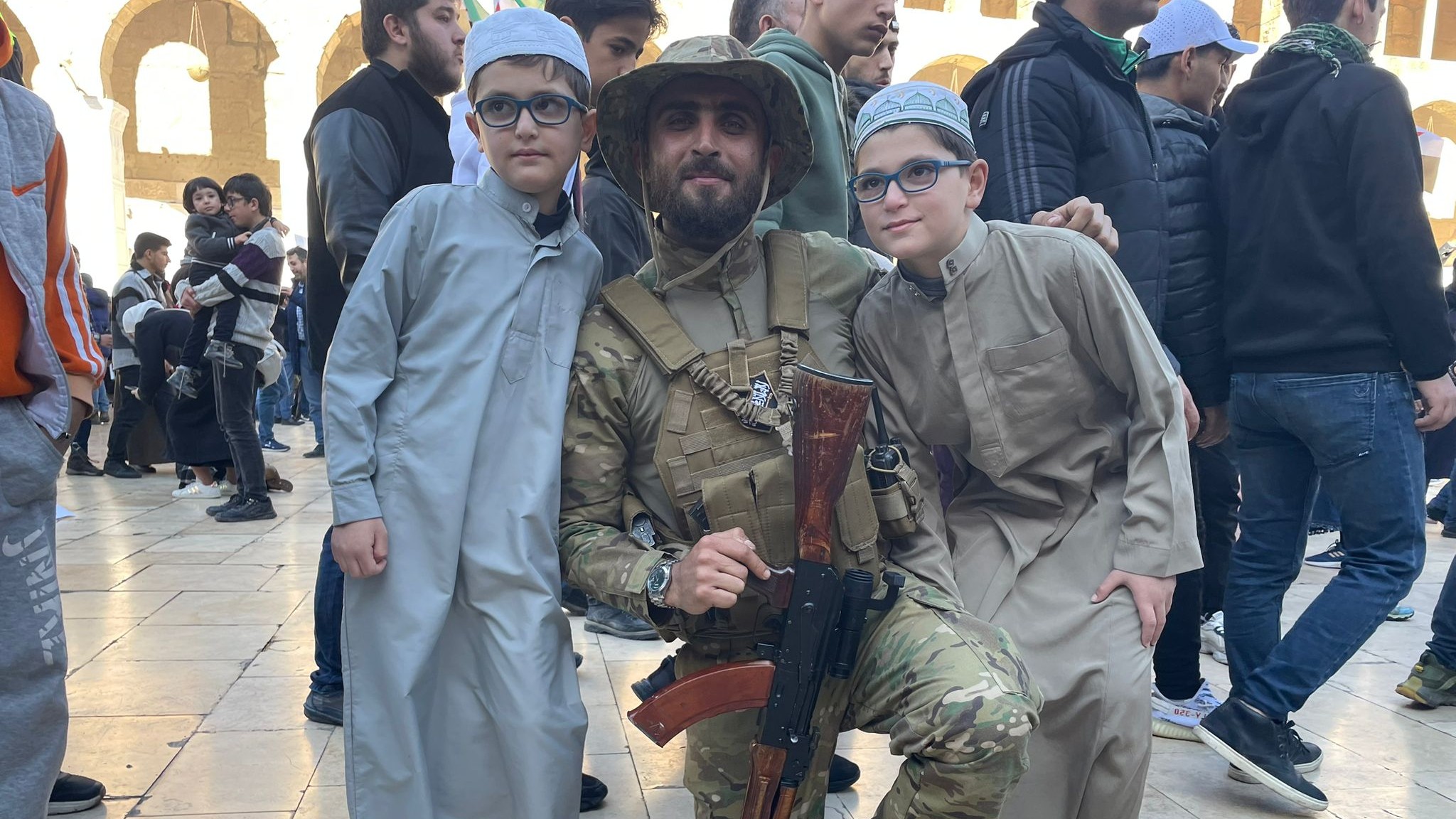 Young Syrians pose with a rebel fighter in the courtyard at the Umayyad Mosque on Friday (Daniel Hilton/MEE) 