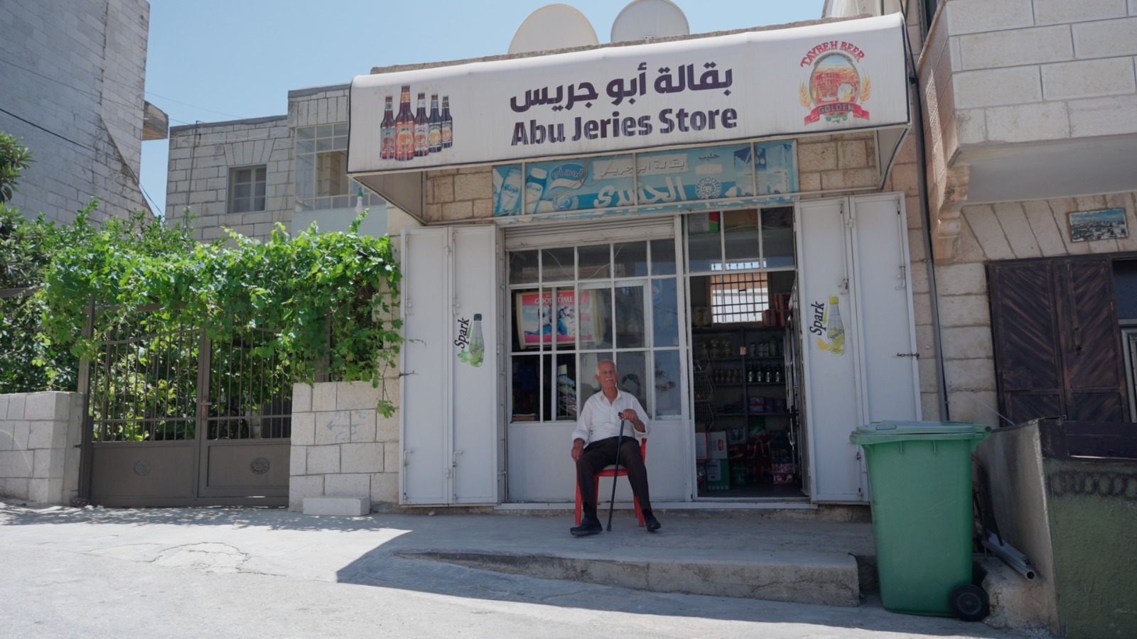 A man sits outside a store in Taybeh (supplied)