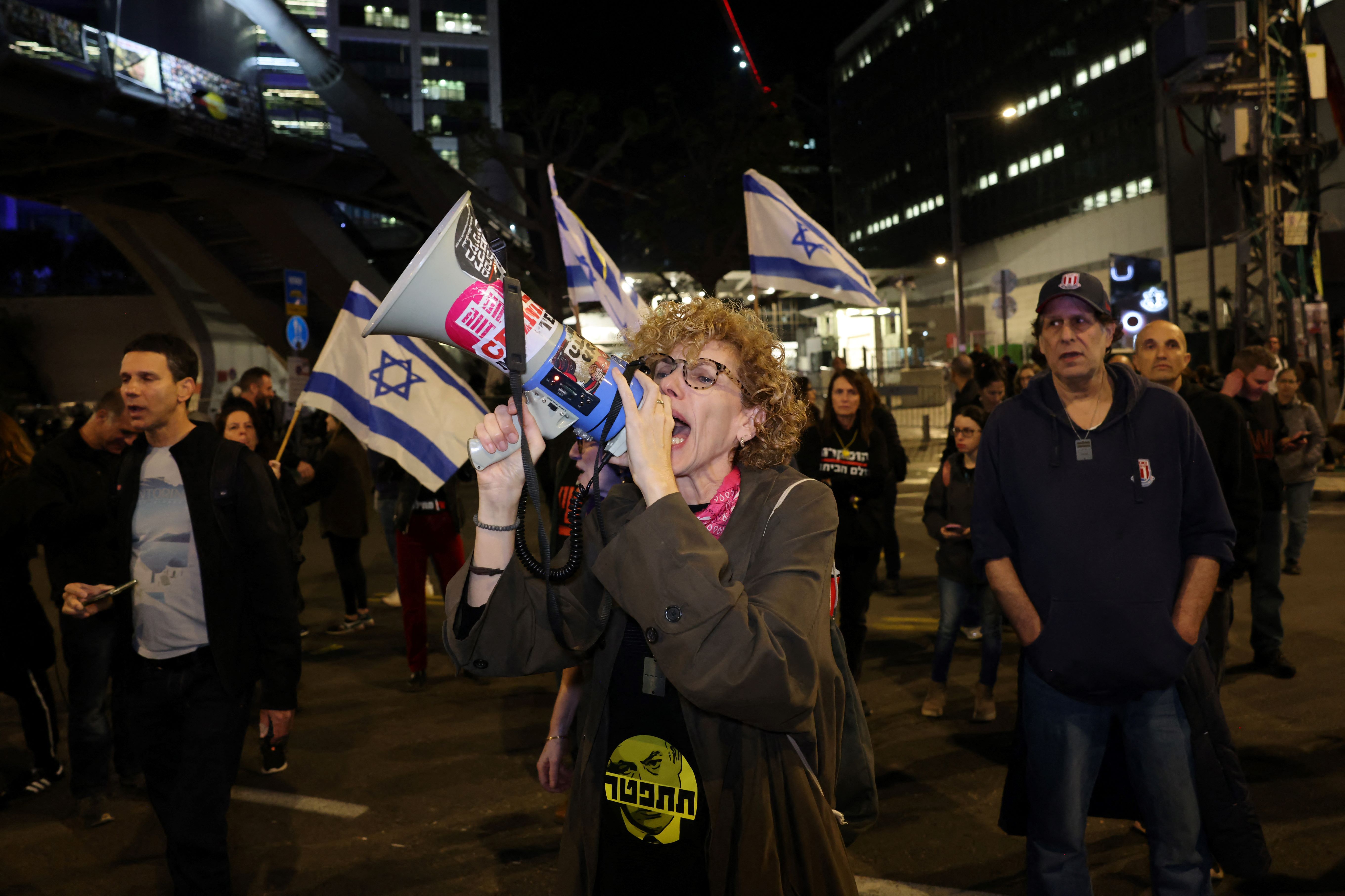 A woman speaks in a megaphone during a rally of relatives and supporters calling for the release of Israeli hostages in Gaza and new elections in Israel (AFP/Ahmad Gharbali)
