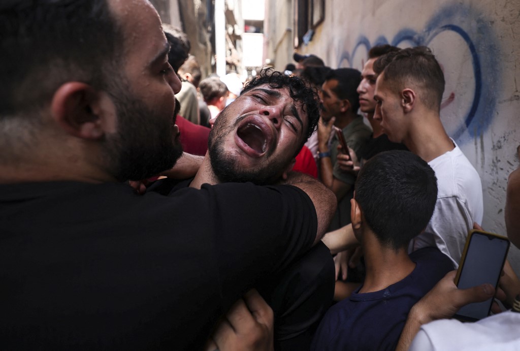 The friend of a young Palestinian killed during the night in the Jabalia refugee camp in the northern Gaza Strip, reacts during his funeral in the same camp, 7 August 2022 (AFP)