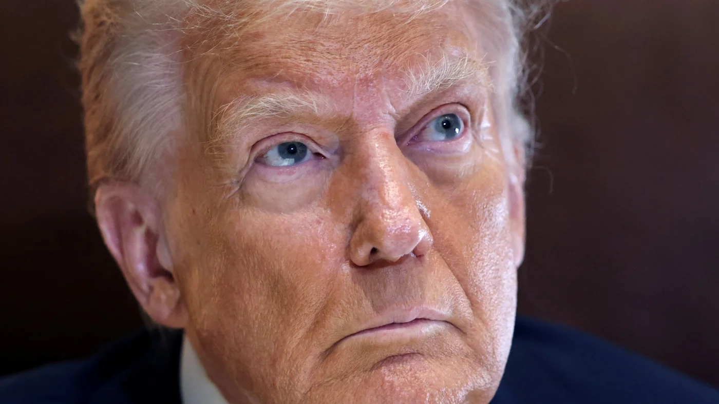 US President Donald Trump looks up while speaking to reporters from his office aboard Air Force One, en route to New Orleans to attend the Super Bowl, on 9 February 2025 (Kevin Lamarque/Reuters)