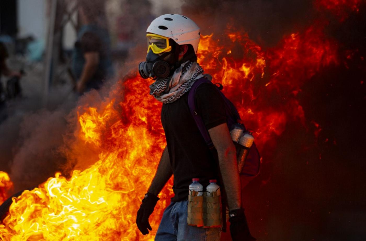 Un manifestant se tient à côté de pneus en feu près de la maison du gouverneur, le 17 août à Bassorah (AFP)