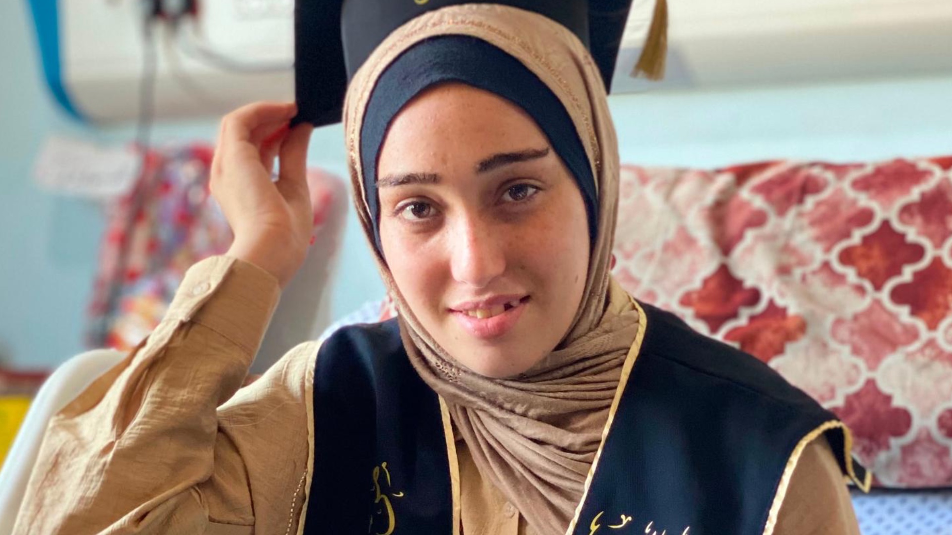 Maram Muqit wears a graduation cap and sash from her hospital bed after completing her Tawjihi exams on 28 July (Provided)