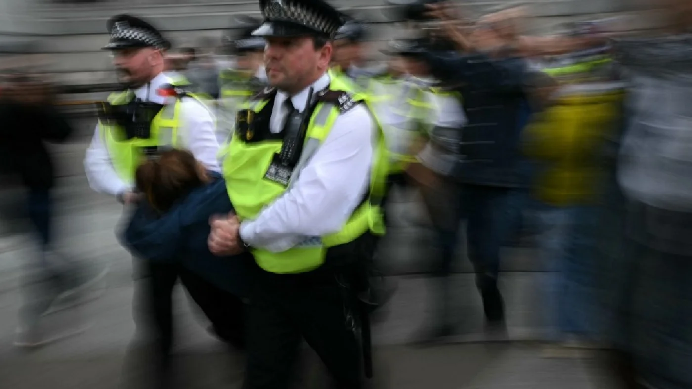 A protester is taken away by police officers at a protest in support of the proscribed group Palestine Action in central London on 4 October (AFP)