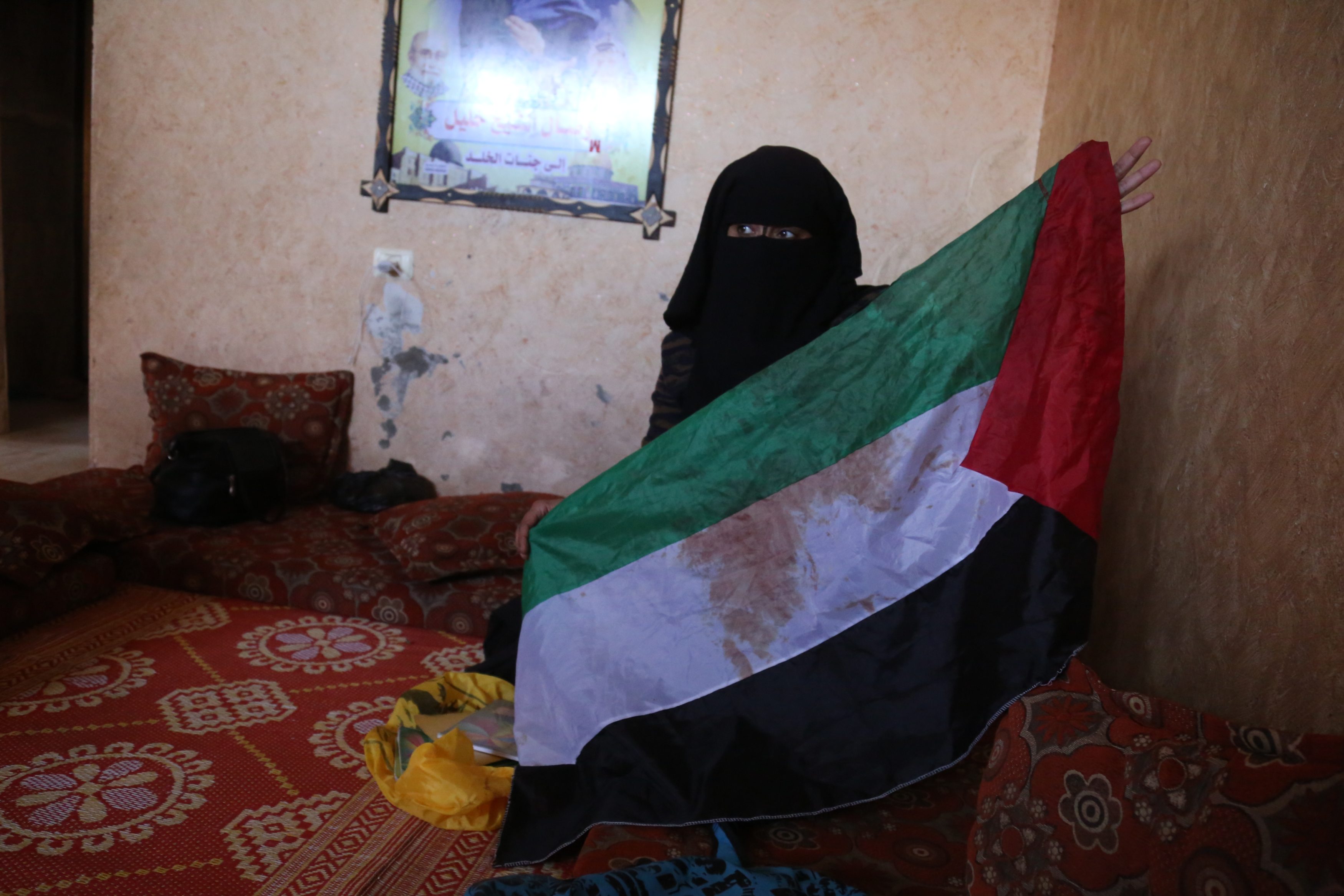 Reem Abu Irmana holds up the bloodied Palestinian flag her daughter Wassal would wave during demonstrations (MEE/Samar Abu Elouf)