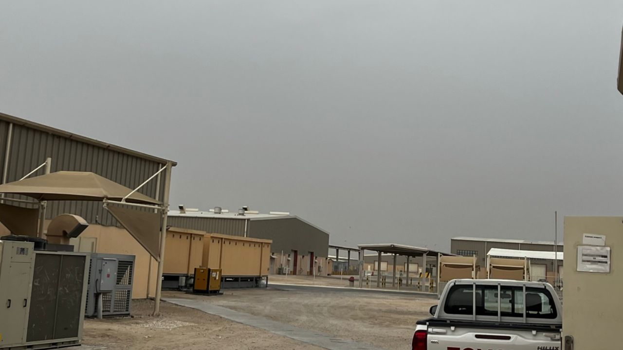 The view from inside Camp As Sayliyah in Qatar shows containers and trucks under a cloudy desert sky