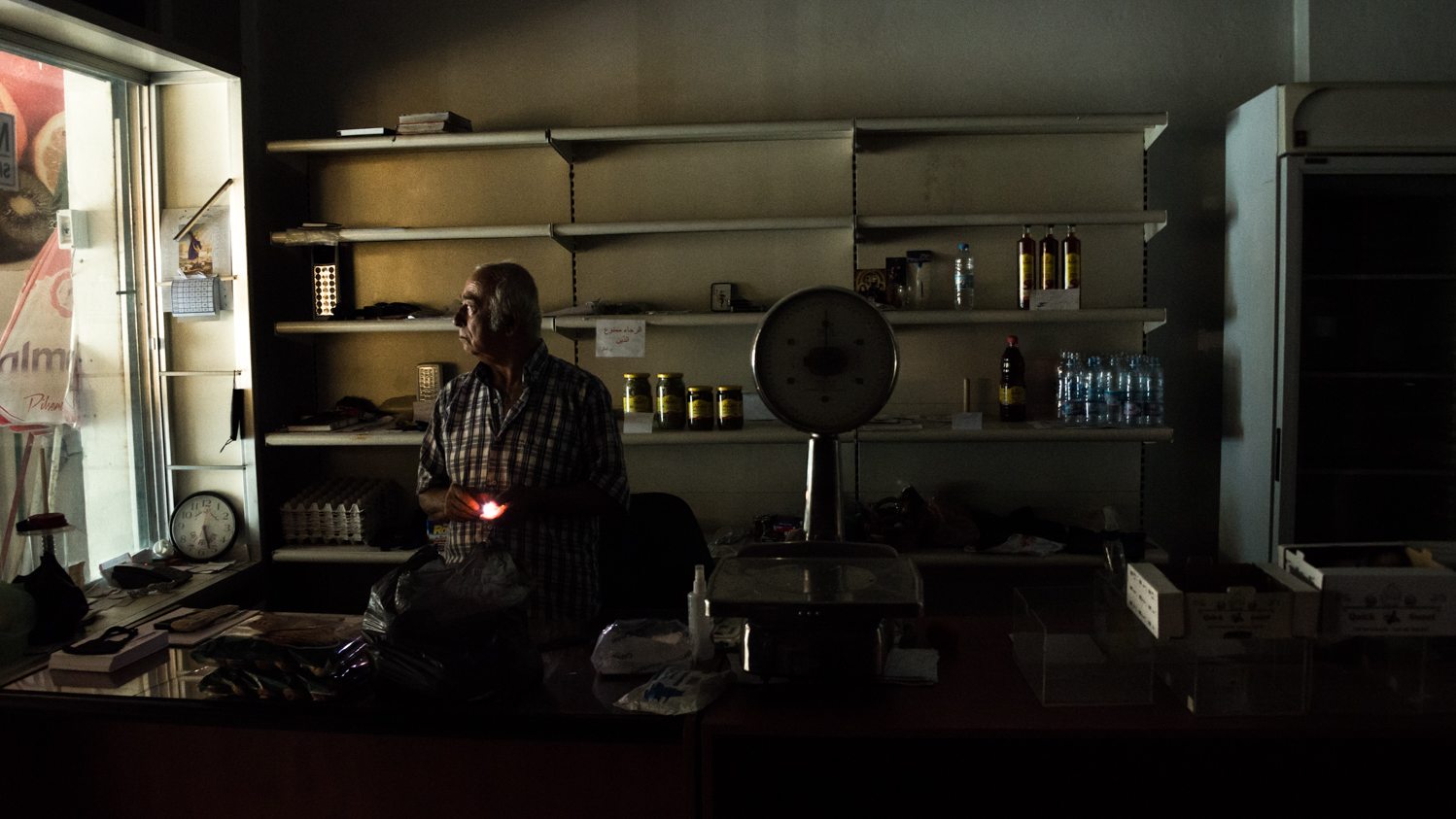 A grocery store, its shelves nearly empty, is plunged in darkness amid omnipresent power cuts in the Beirut suburb of Zouk Mikael on 25 August 2021 (MEE/Elizabeth Fitt)