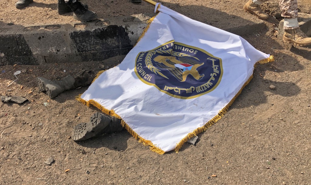 A victim of the Aden military parade attack is covered by an STC flag on 1 August (AFP)