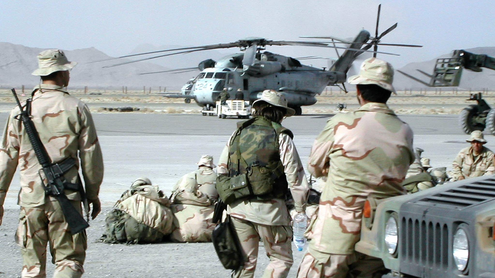 US Marines watch a helicopter prepare to leave a US base at Kandahar airport on 23 January 2002 (Banaras Khan/AFP)