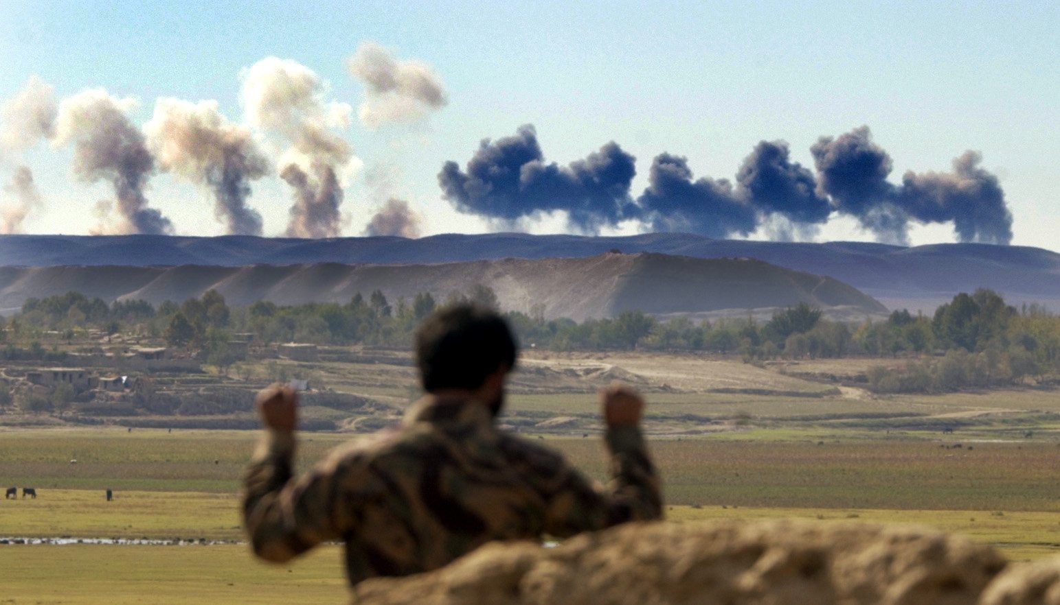 An Afghan Northern Alliance soldier watches the US bombardment of a ridge occupied by Taliban, near Khoja Bahauddin, Afghanistan, in October 2001 (Peter Nicholls/The Times)