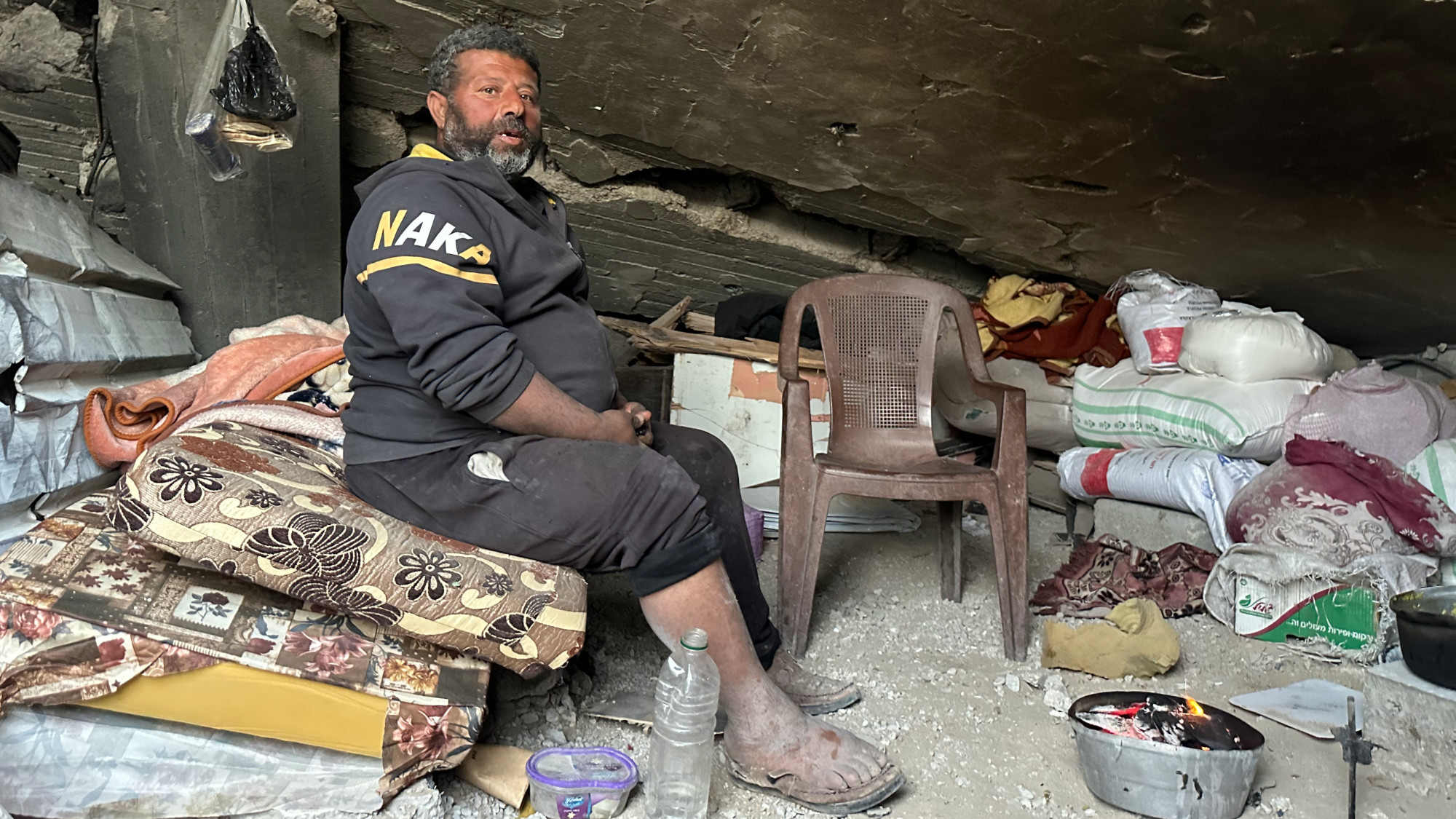 Ibrahim Khalid sits amongs the rubble of his family's destyored house in Gaza City (MEE/Ahmed Dremly)