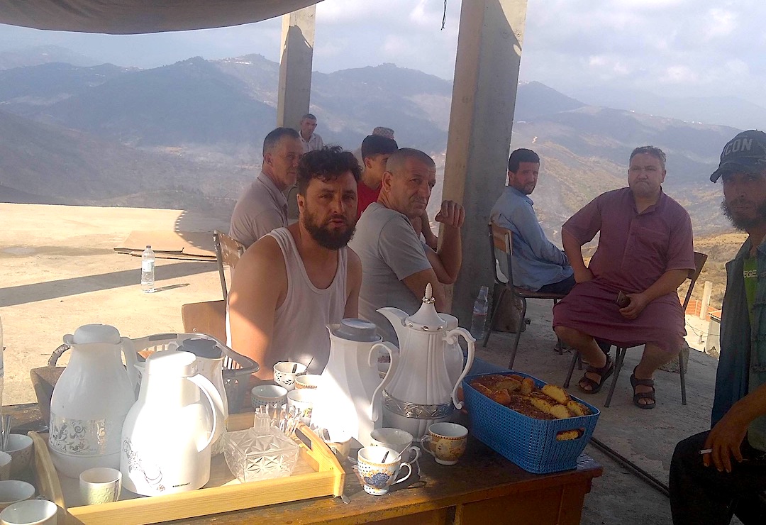 Villagers have set up a makeshift camp in an unfinished house to welcome visitors and donations. Coffee pots, teapots and boxes of cakes are laid out on a table (MEE/Ali Boukhlef)