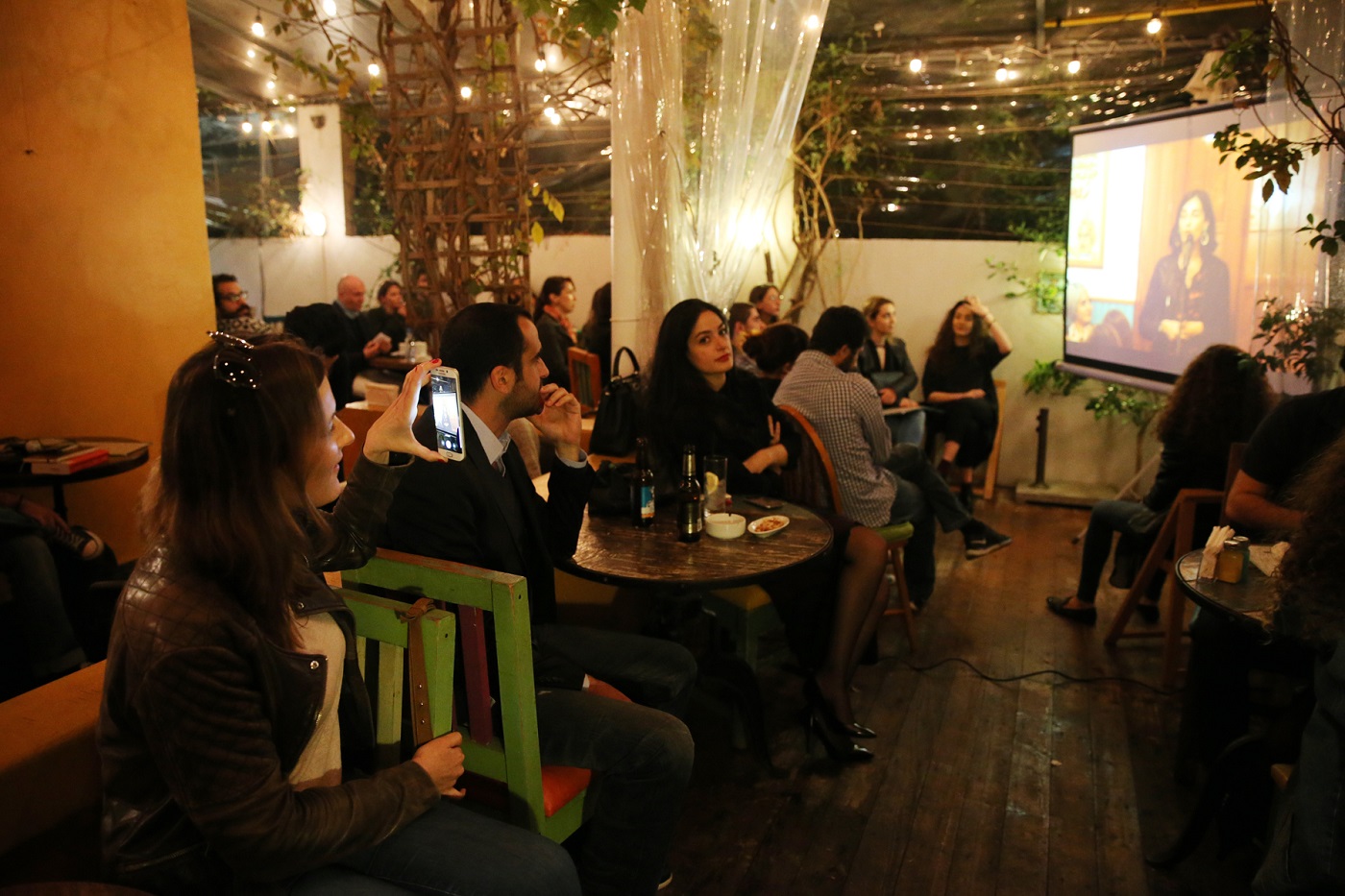 Des spectateurs regardent une conteuse traditionnelle sur grand écran (Dar al-Mussawir)