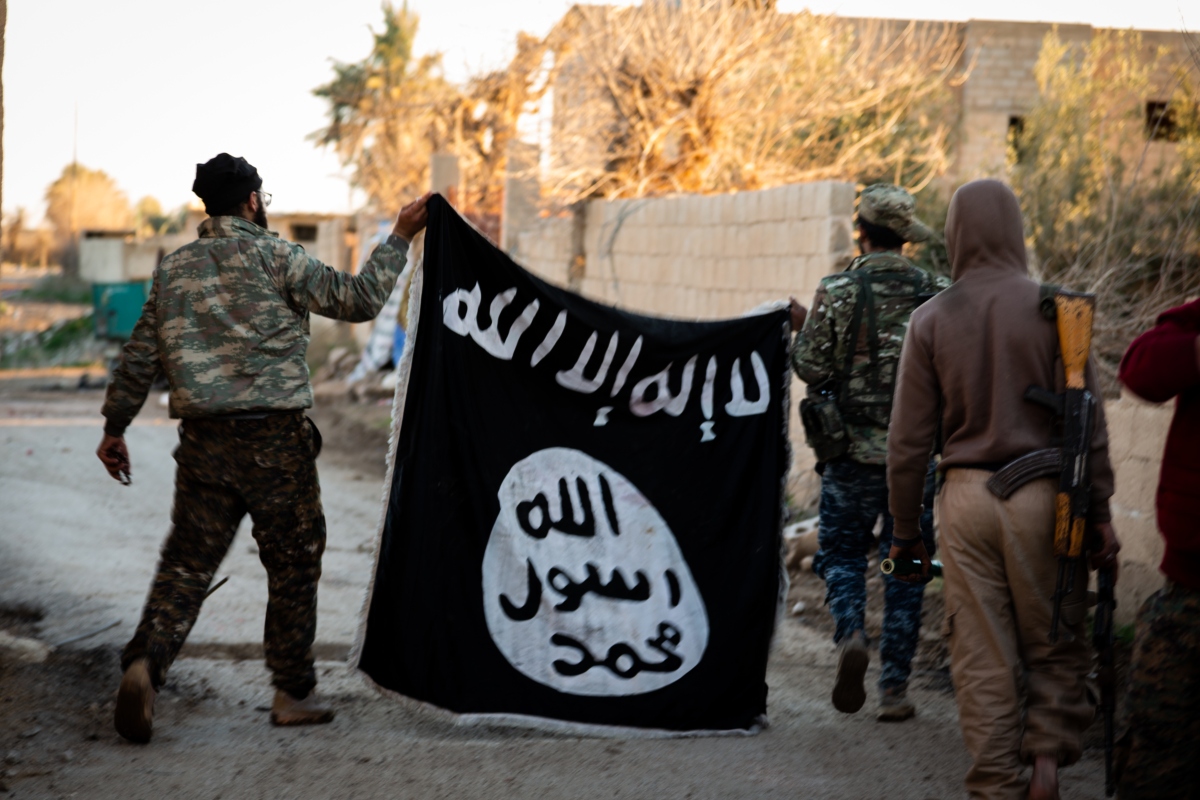 On the ground soldier find the black ISIS banner. 