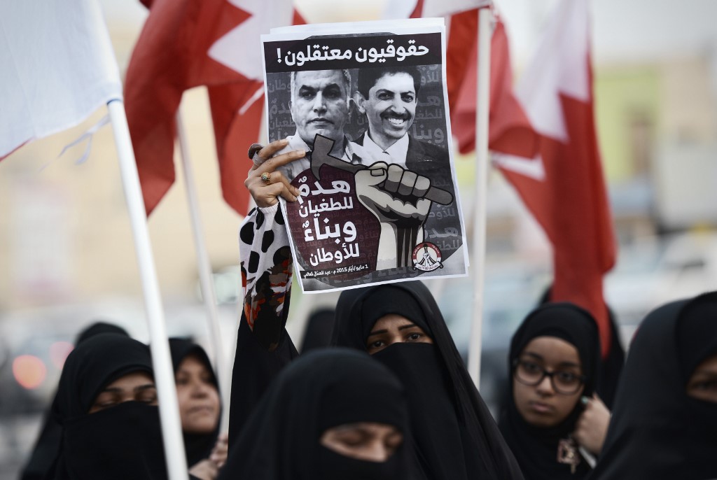 Bahrainis hold up a poster bearing portraits of Rajab and Abdulhadi Alkhawaja during a protest west of Manama in 2015 (AFP)