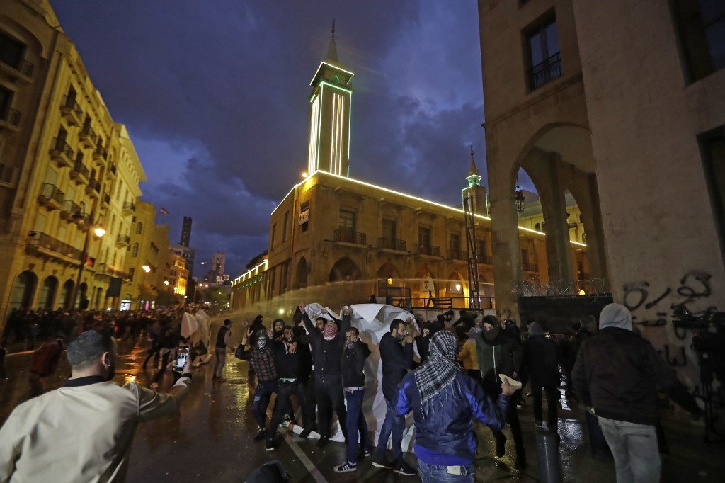 Lebanese anti-government protesters clash with security forces near Parliament headquarters in Beirut on 22 January (AFP)
