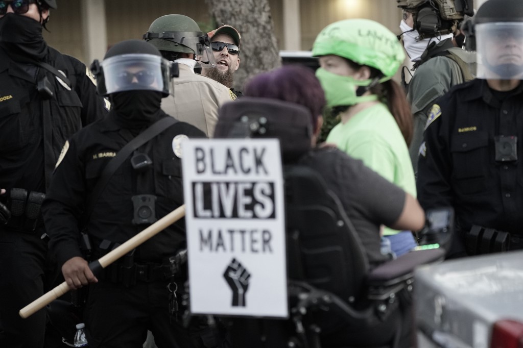 A US far-right militia member shouts towards Black Lives Matter protesters on 1 August (AFP)