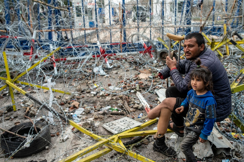 A refugee waits with his child at the Turkey-Greece border on 5 March (AFP)