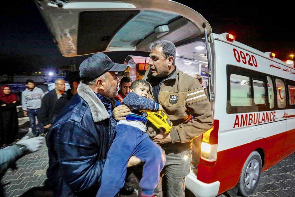 Palestinians carry wounded boy outside hospital in Beit Lahia, northern Gaza Strip, on Sunday night (AFP)
