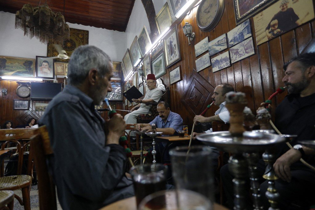 Ahmad al-Lahham, un conteur syrien, lit son livre d’histoires dans un café de Damas, le 19 juin 2017 (AFP/Louai Beshara)